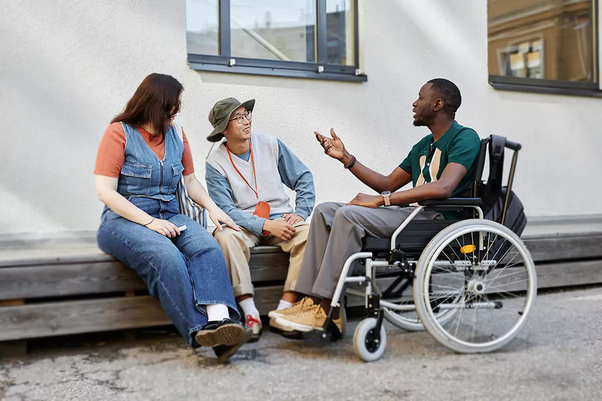 A group of disabled friends are sitting outdoors having a conversation
